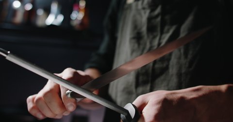 Close up shot of chef sharpening a cool knife before cutting meat or making a meal. Professional cooker preparing an instrument for work 4k footage