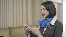 Beautiful flight attendant having video call with her boyfriend by using smartphone in the airport. Smile happy and bye on her phone. Social network, selfie and travel concept. Slow motion video
