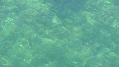 Roppled turquoise transparent water of Barents sea close up view.