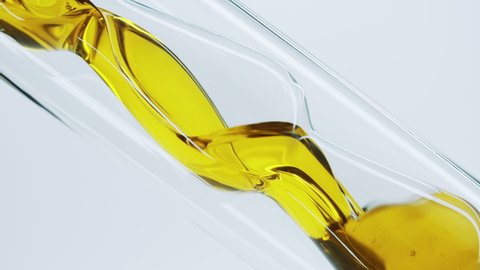 Yellow natural oil flows through a laboratory glass tube. Obtaining essential oils by filtration. Production of natural cosmetics. Сlose-up of glass test tube with oil.