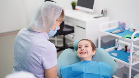 Woman Doctor in a Dental Clinic Talking with Funny Little Boy who Smiles. Work of a Dentist with Children. Healthcare and Medicine Concept. High quality 4k footage