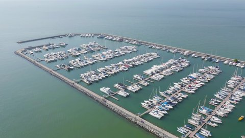 Aerial view of sail boats in marina port in harbor, ocean or bay with blue turquoise seawater in urban city or town, Pattaya in travel trip and transportation concept. Top view.