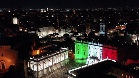 Italian flag illuminates the facade of the Capitol. Aerial view with drone on Alatre della Patria and the Imperial Forums. Night, Rome