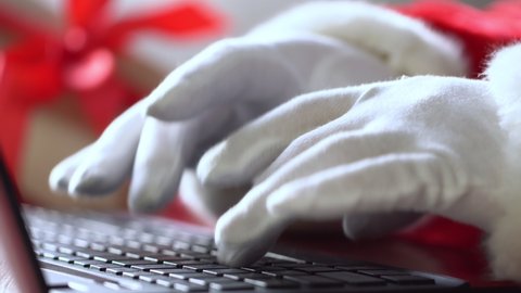 Santa Claus typing on a laptop Keyboard. Christmas and new year celebration. Winter holidays. Hands close up.