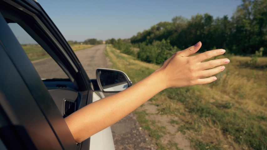 Girl hand in car window. Car trip at sunset. Happy family. Girl hand greeting in car window. Summer family trip at sunset. Family car travel concept. Happy girl hand in window. Family happy vacation. Royalty-Free Stock Footage #1063981372