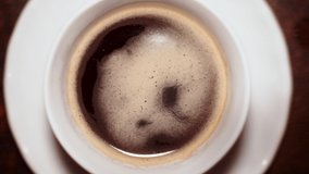Drop of freshly brewed coffee falling into the cup. Slow motion video.