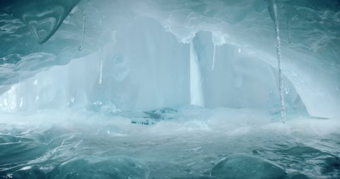 Beautiful ice cave with icicles and amazing light. Gentle camera movement through a frosty turquise  ice cave in 4k.