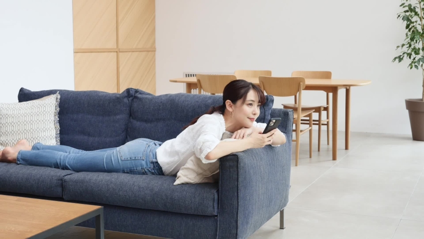 Asian woman using the smartphone on the sofa