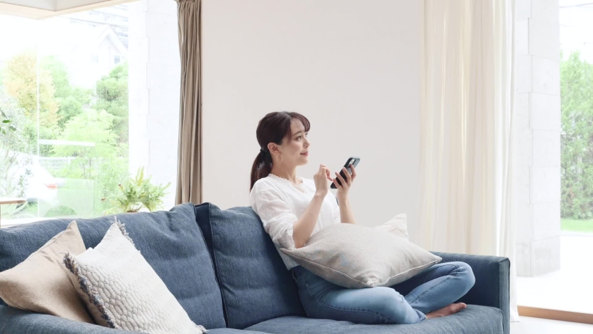Asian woman using the smartphone on the sofa Royalty-Free Stock Footage #1063985599