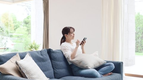 Asian woman using the smartphone on the sofa