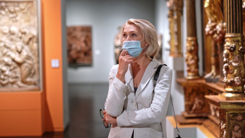 woman visitor in historical museum looking at art object