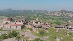 Aerial orbiting shot of Krishnagiri Fort Building complex standing on green mountain.Fields and river in the valley.Sunny day in India.