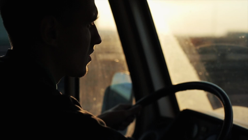 A young man is driving down a busy highway in his van and staring intently at the road. Side view from inside the cab | Shutterstock HD Video #1063995679