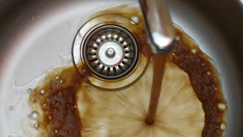 Streaming dirty rusty brown water in sink. Water stream going down the drain. | Shutterstock HD Video #1063997065