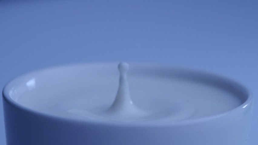 Milk drop falls into the filled cup created ripple wave in slow motion. | Shutterstock HD Video #1063998580