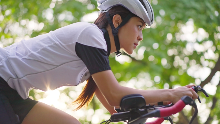 Asian young beautiful woman riding bicycle for health in the evening in public park. The athlete fit and firm girl in sportswear exercising by cycling workout sport for her healthy wellness. | Shutterstock HD Video #1063999114