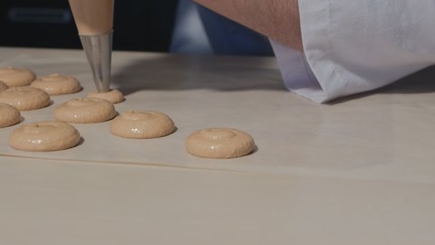 pastry chef squeezes macaroon dough onto parchment for baking. Italian meringue macaroon. Confectionery manufacturing. dolly video
