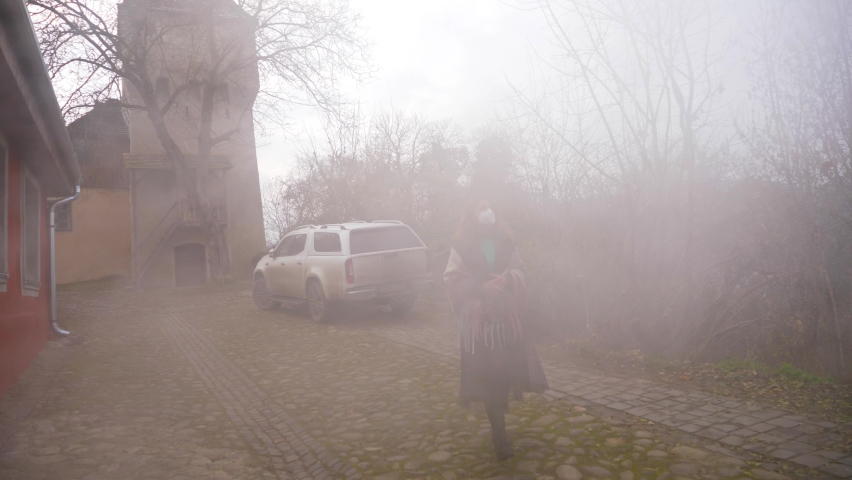 Girl with mask appears from the fog.Young 
girl with mask goes through the steam