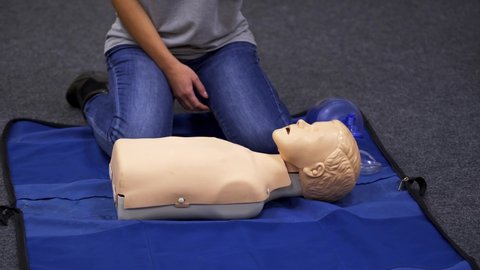 Baby CPR dummy first aid training. Paramedic performing cardiopulmonary resuscitation on baby dummy with chest compression