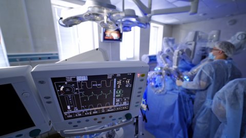 Artificial lung ventilation monitor in the intensive care unit. Group of surgeons in operating room with surgery equipment.