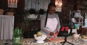 African senior woman cooking outdoor while streaming online for webinar masterclass lesson at home - Food and influencer concept 