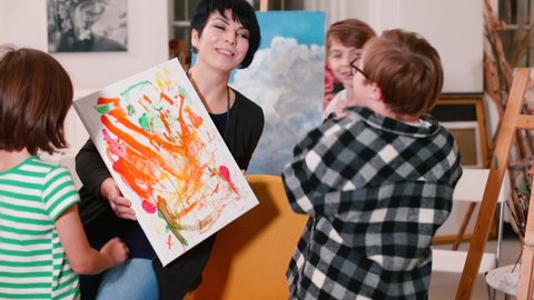 Woman with kids. Support staff during inclusive art education. Collaboration between all team members is the best strategy for success. Down Syndrome support professional program. 