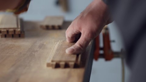 woodworker grinds the grooves on the wood piece with sandpaper for further bonding. carpentry handmade.