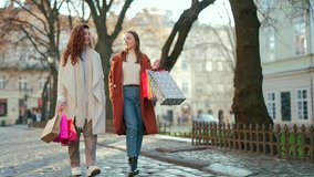 Two happy young women walking around the city after shopping on a city street in coats with gift bags in cold autumn winter or spring weather 2 cheerful girls go outside from a sale in a mall or store - Powered by Shutterstock - Get 15% off with code: PIKWIZARD15