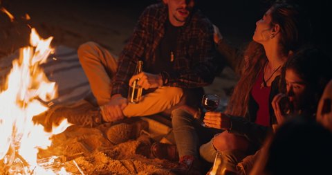 Girl drinking wine glass with friends on bonfire at night