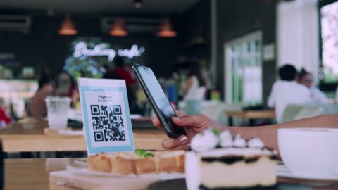 Women using their phones for scanning to pay for coffee and cake on cafe. Mobile scanning system oline for pay money . Concept technology for pay by scan QR code.