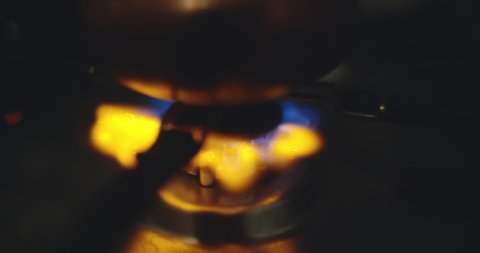Macro shot of firing a hotplate. Slow motion of lighting a burner in dark kitchen. Preparing for cooking. Blue gasoline flame. Cinematic light. Burning gas.