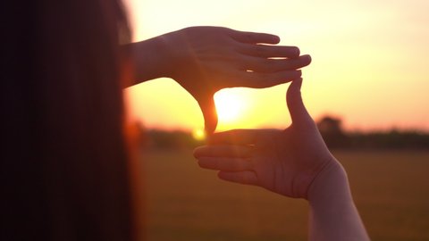 Future planning concept, Woman hands making frame gesture with sunset, Female capturing the sunrise.