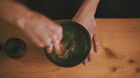 Shot of chawan ceremony bowl with green color matcha tea powde.
Hot water into the Japanese clay cup for one person.
Whipping matcha tea process
tea room shop.
Evening light and atmospher.