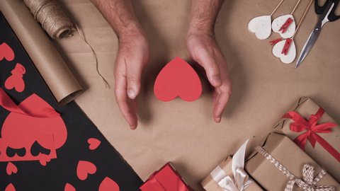 male hands put a box in the shape of a heart on the table. . Valentine's day gift concept. Stock Video