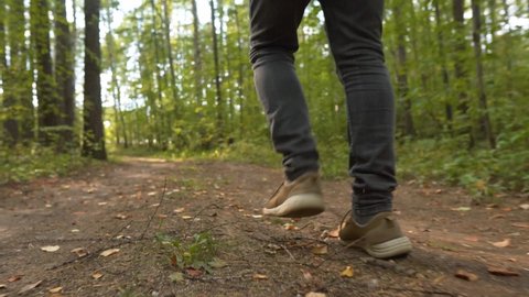Man Walks along the Forest. Tourist in Boots Going along the Road on the Background a Beautiful Landscape. Travel Concept Active People on the Way to Victory Move Forward Close Up.