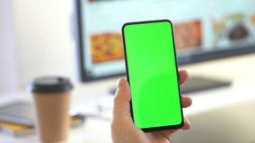Handheld Camera: Back View of Brunette Man Holding Chroma Key Green Screen Smartphone Watching Content Without Touching or Swiping. Boy Using Mobile Phone, Browsing Internet, Watching Content,