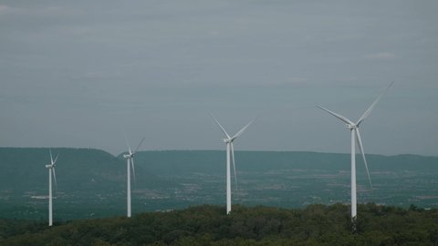 Bangkok, Thailand - December 9, 2020 : Aerial view of windmills turning at sunset, Wind turbines close-up on forest on cloudy day, 4K aerial video. (Electricity Generating Authority of Thailand)