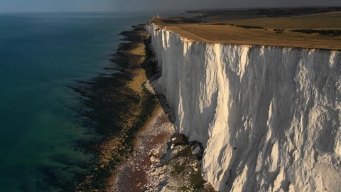 Landscape aerial drone footage video of a Beachy Head Lighthouse and chalk cliffs at colourful sunrise  with low tide in England, near Eastbourne