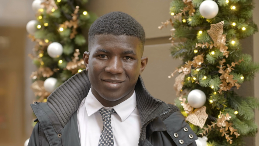 Happy black african youg man smiling at camera at Christmas- outdoor