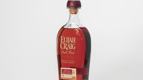 Thessaloniki, Greece - December 14 2020: Elijah Craig alcoholic bourbon drink rotating. Small Batch edition of Kentucky Straight Whiskey on 750 ml bottle with logo, against white background.