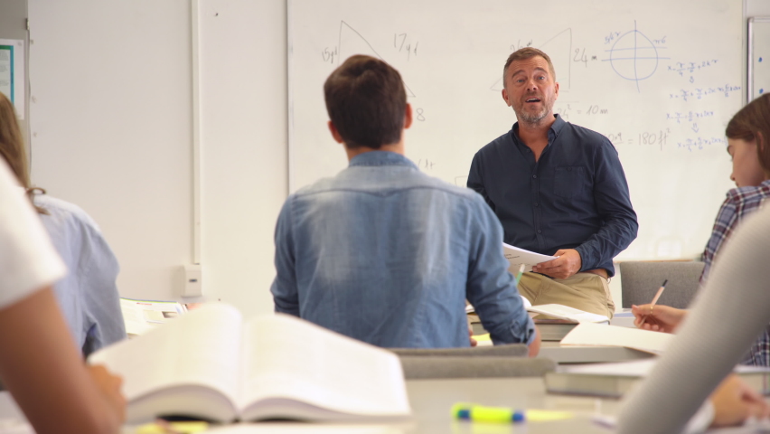 Professor pointing at college student with hand raised. Student raising a hand with a question for the teacher. Lecturer teaching in class while girl have a question to do during a math lesson. Royalty-Free Stock Footage #1064040613