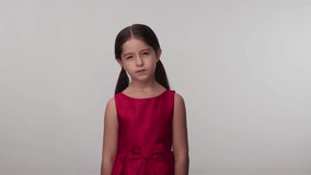 Little girl in red dress wearing casual clothes smelling something stinky and disgusting, holding unbearable smell, breathing fingers on nose.Slow motion video.