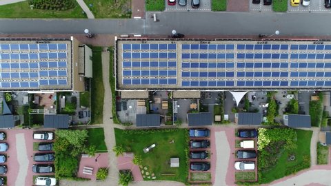 Aerial top down view of new built apartment complex with solar panels installed on the roof from which the photo voltaic cells use sunlight as a source of energy and generate electricity 4k quality