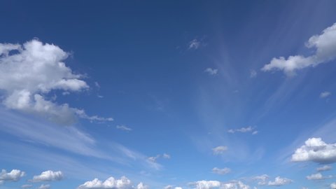 Video timelapse of clear sunny blue sky with soft fluffy white clouds moving along. Natural background.