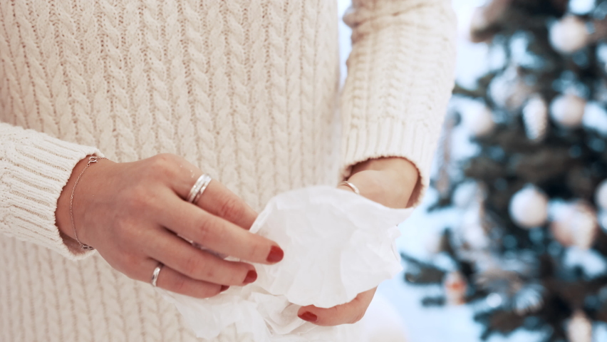 Girl with a white hat in the forest with a backpack and hiking sticks in winter. Back view