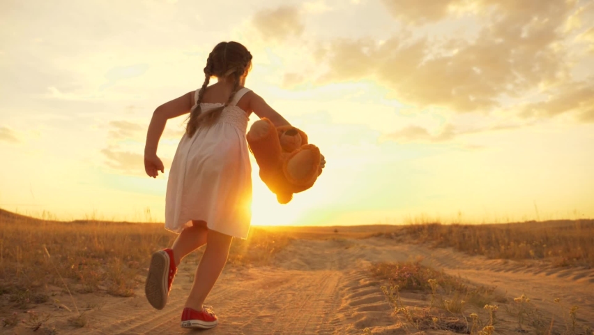 Little girl with a toy teddy bear in park. Cute girl with a teddy bear in a green field. Lonely girl with a toy teddy bear in park in green field.Teddy bear in the hands of a girl in the park | Shutterstock HD Video #1064059012
