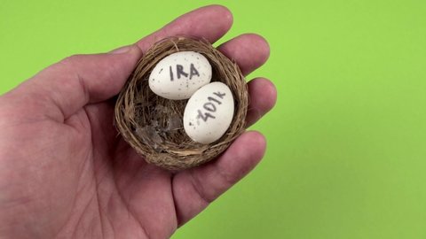 Conceptual composition. Pension savings. The man holds in his hand three eggs with the inscriptions IRA, 401k, Roth which lie in the nest. Close-up