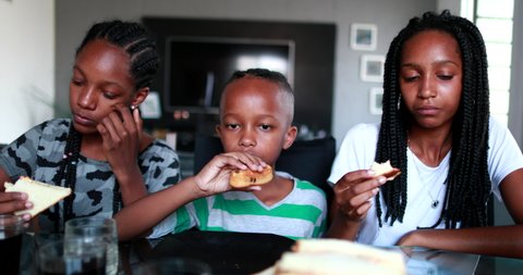 Children eating afternoon snack at home. Black African ethnicity kids snacking sandwiches