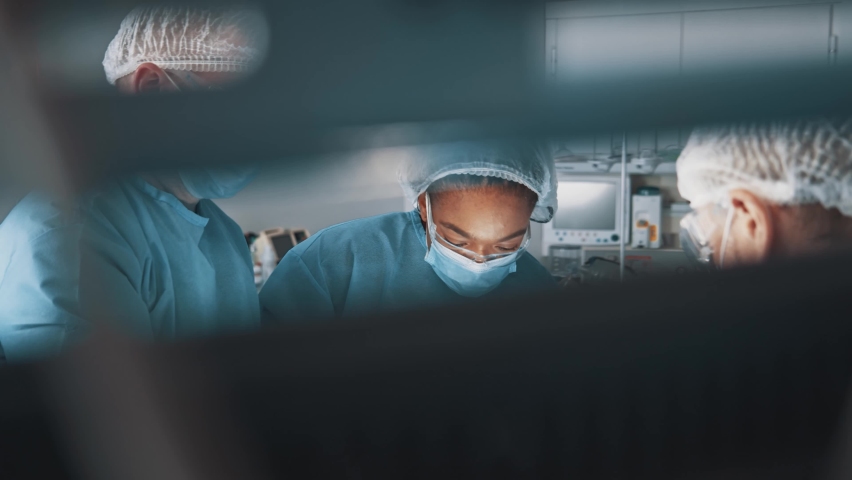 Diverse mixed-race surgeon afro-american woman with several doctors performing medical surgery operation in operating room modern hospital collaborating. Royalty-Free Stock Footage #1064071963