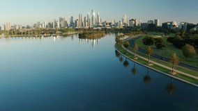 Aerial video of beautiful park with lake and Melbourne CBD at sunrise